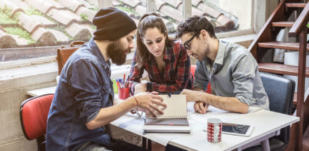 Three people at table studying notes