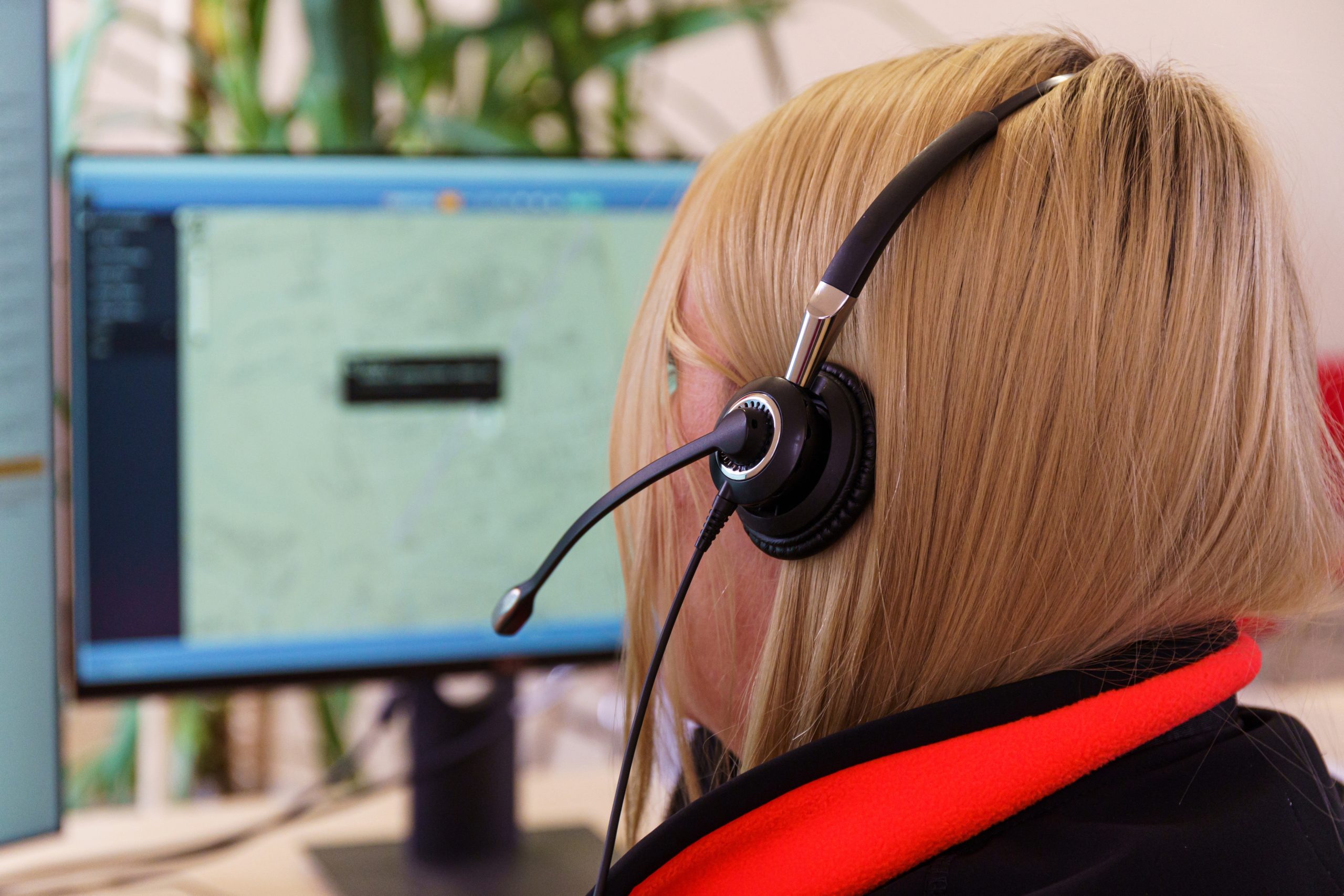 Woman looking at computer screen wearing a headset.