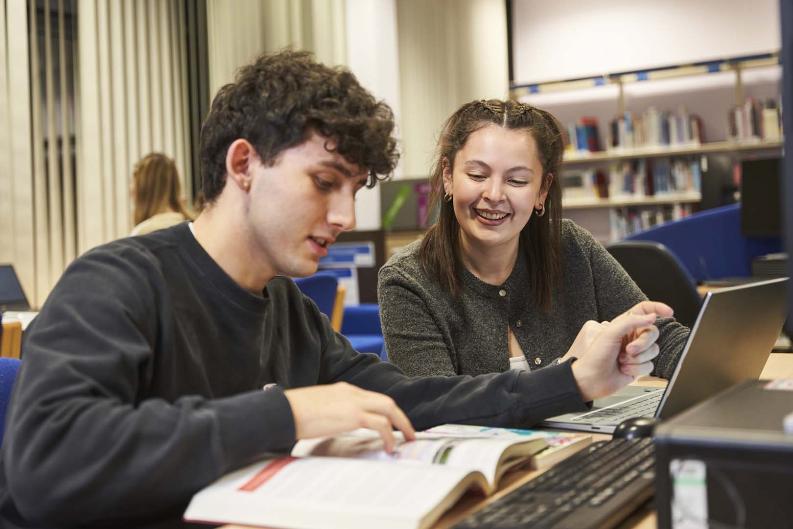 College lecturer and learner looking at book in library