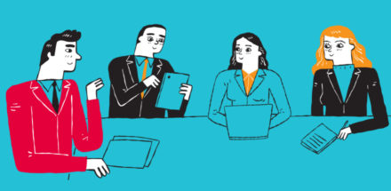 People sitting around table in office working on laptop