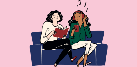 Two young people sitting on a sofa. One is reading a book and the other is listening to music.